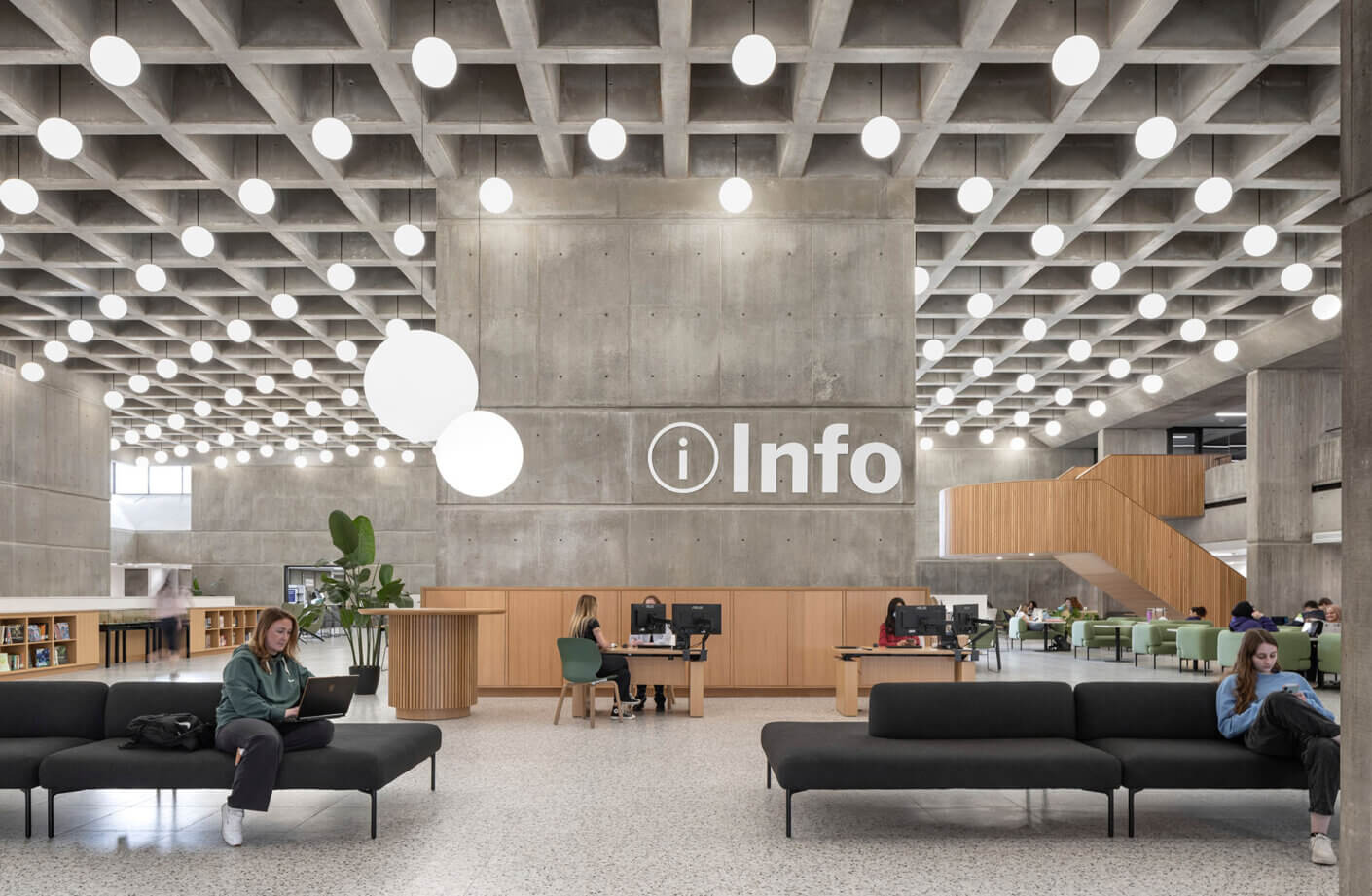 A straight-on view of the atrium taken from the ground. Two girls sit on couches in front of a large desk with an